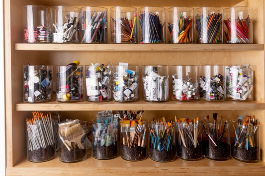 glass jars hold a collection of art supplies, paints, brushes, pencils, it's described as the artist's art pantry, ready to create