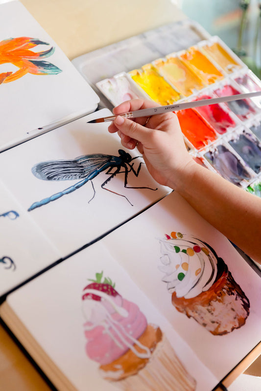 watercolor sketchbook paintings of cupcakes, insects, and fish